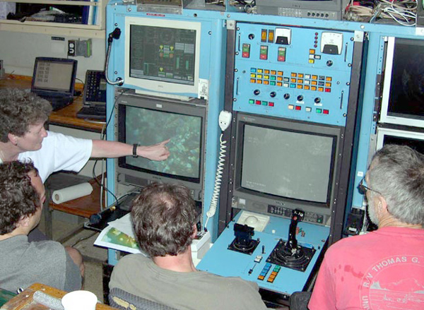 Team is gathered around the ROPOS console, identifying vent species on the seafloor.