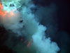 An explosion near the summit of West Mata volcano throws ash and rock, and molten lava glows below. 