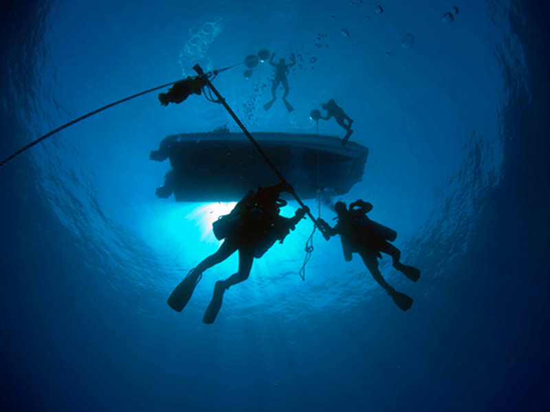 Silhouettes of the team at the deco bar and at the surface waiting for divers to return from the last dive.