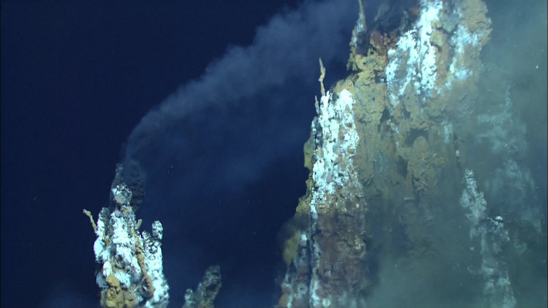 Black smoke from the top of a chimney is carried “downwind“ by the strong current in the vent field.