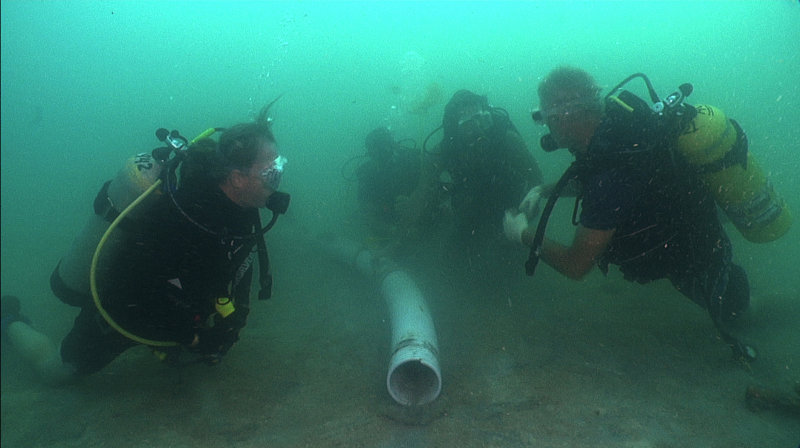 The research team divers positioning the end of the dredge hose for excavation (Dr. Hemmings, Dr. Loebel, Ben Wells, and Holly Perdue).