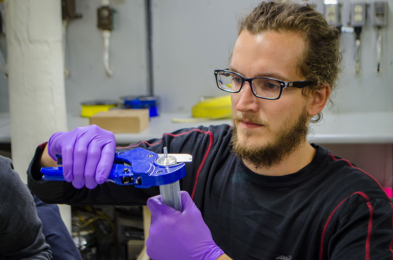 Kyle Dilliplaine cuts a syringe as smoothly as possible to be used on the box core to take samples of benthic bacteria. 