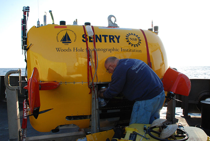 While we’ve already sent previous batches of cups down on the CTD cast to depths greater than 1,200 meters, we’ll be sending this round down on AUV Sentry to a depth of approximately 600 meters. Here, mechanical engineer Andy Billings works to secure the cups in the vehicle’s center compartment.