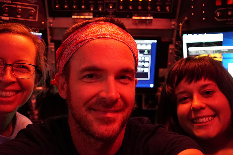 Amanda Demopoulos, Jefferson Grau, and Caitlin Adams capture a selfie from inside the compact pressure hull of the human-occupied vehicle Alvin during a DEEP SEARCH 2018 expedition dive.