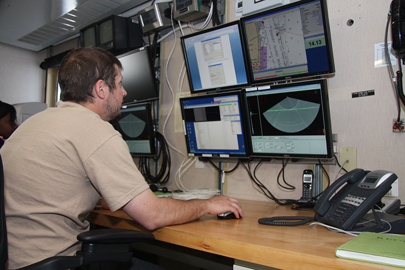 Senior Survey Technician David Moehl at the controls of Hassler’s multi-beam echosounders in the ship’s Survey Lab. Hassler is equipped with several different seabed mapping systems, each optimized for a different depth range.