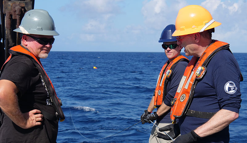 Chief Bosun Mike Collins, Larry Mayer (University of New Hampshire - Center for Coastal and Ocean Mapping) and Robert Mills (JASCO) payout the hydrophone array mooring line.