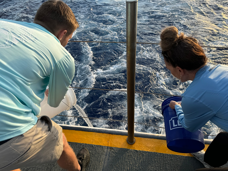 Image of cultural liaisons Makoa and Malia pouring their water over the fantail.