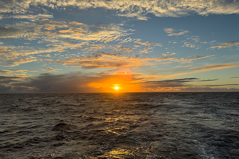 Image of the June 30 Sunday sunrise during the Beyond the Blue: Papahānaumokuākea Mapping 1 expedition. The clouds cleared by the end of our chant to reveal a beautiful orange sun.