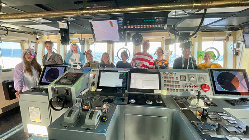 A group of people in Halloween costumes standing on the bridge of the Okeanos Explorer.