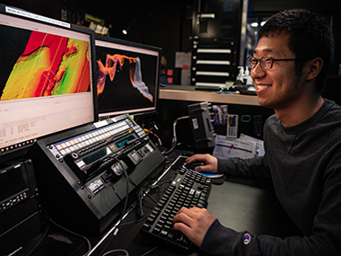 Explorer-in-training Edward Kim works to process multibeam bathymetry data collected during an expedition on NOAA Ship <i>Okeanos Explorer</i>. Three explorers-in-training will join the Beyond the Blue: Papahānaumokuākea Mapping 1 expedition in this role.